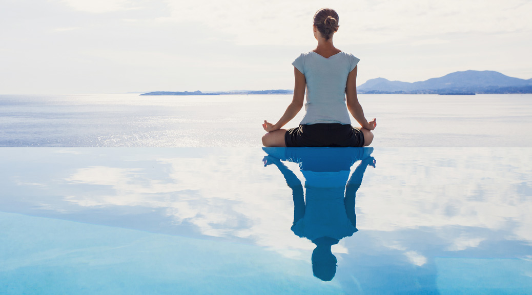 Young woman practicing yoga outdoors at swimming pool side.