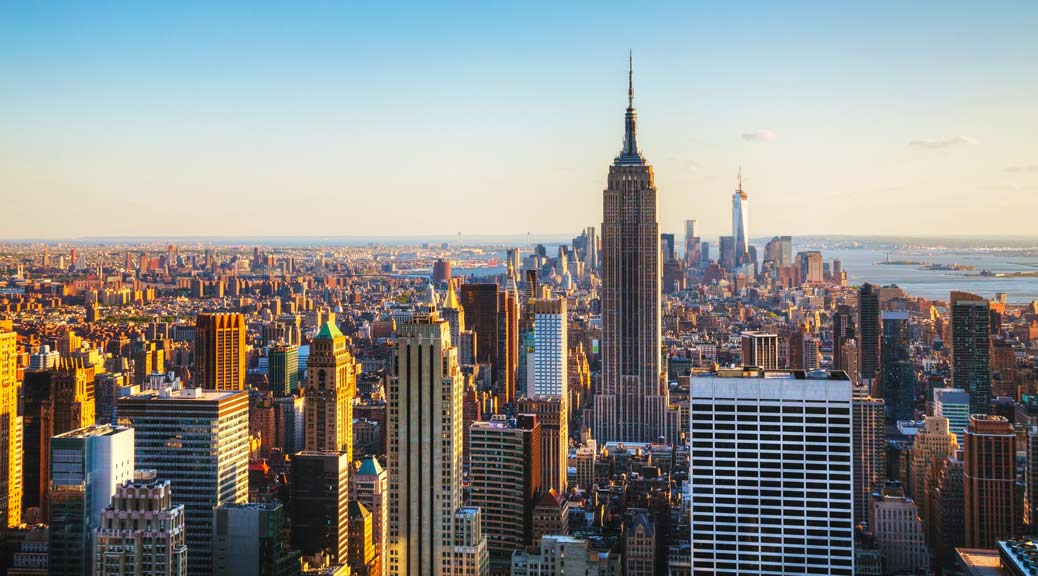 Manhattan downtown skyline with illuminated Empire State Building and skyscrapers at sunset