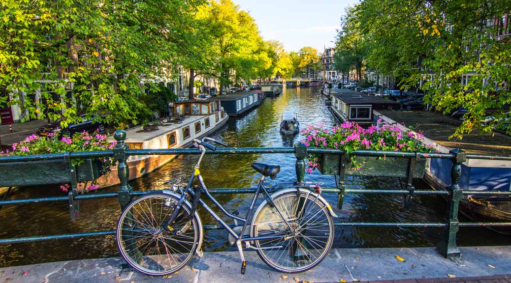 Bicycle parked on the bridge over the canals on a bright sunny day in amsterdam