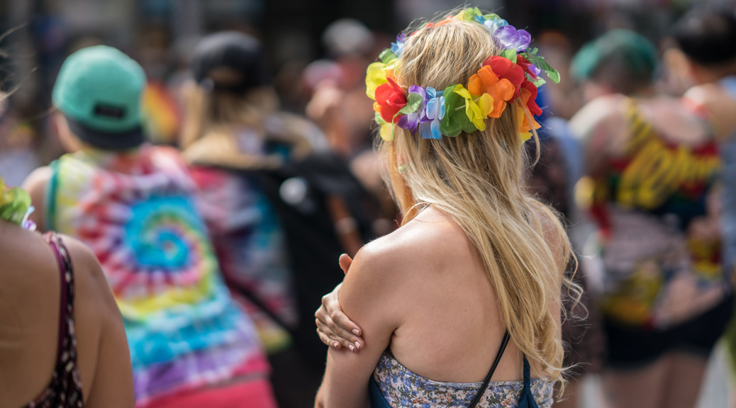 Young blonde woman in a crowd celebrating Pride Parade. Wearing colorful rainbow accessories and a flower crown at Triton Square in Valletta, Malta.