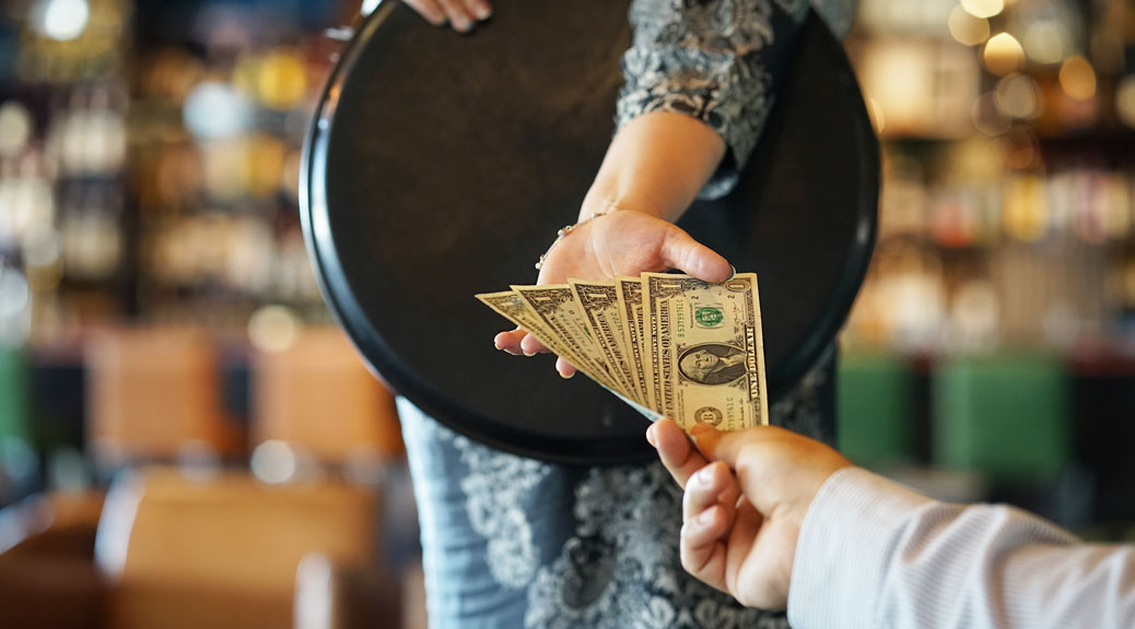 waiter girl receives a tip from the client at the hotel bar