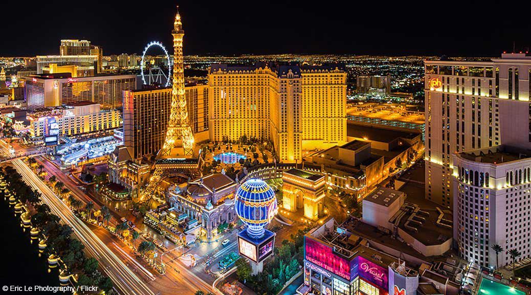 Replica of Eiffel tower a giant ferris wheel and 5 star hotels and casinos lit up in golden lights at night in las vegas